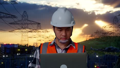 primer plano de un ingeniero masculino asiático con casco de seguridad trabajando en una computadora portátil mientras está de pie cerca de una torre de alto voltaje