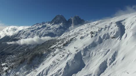 Drone-Footage-of-Snowy-Mountain-Peak-Above-Cloud-Filled-Valley