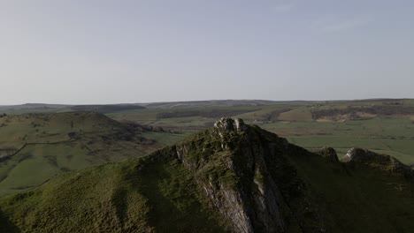 an aerial drone shot flying over a mountain peak in the peak district