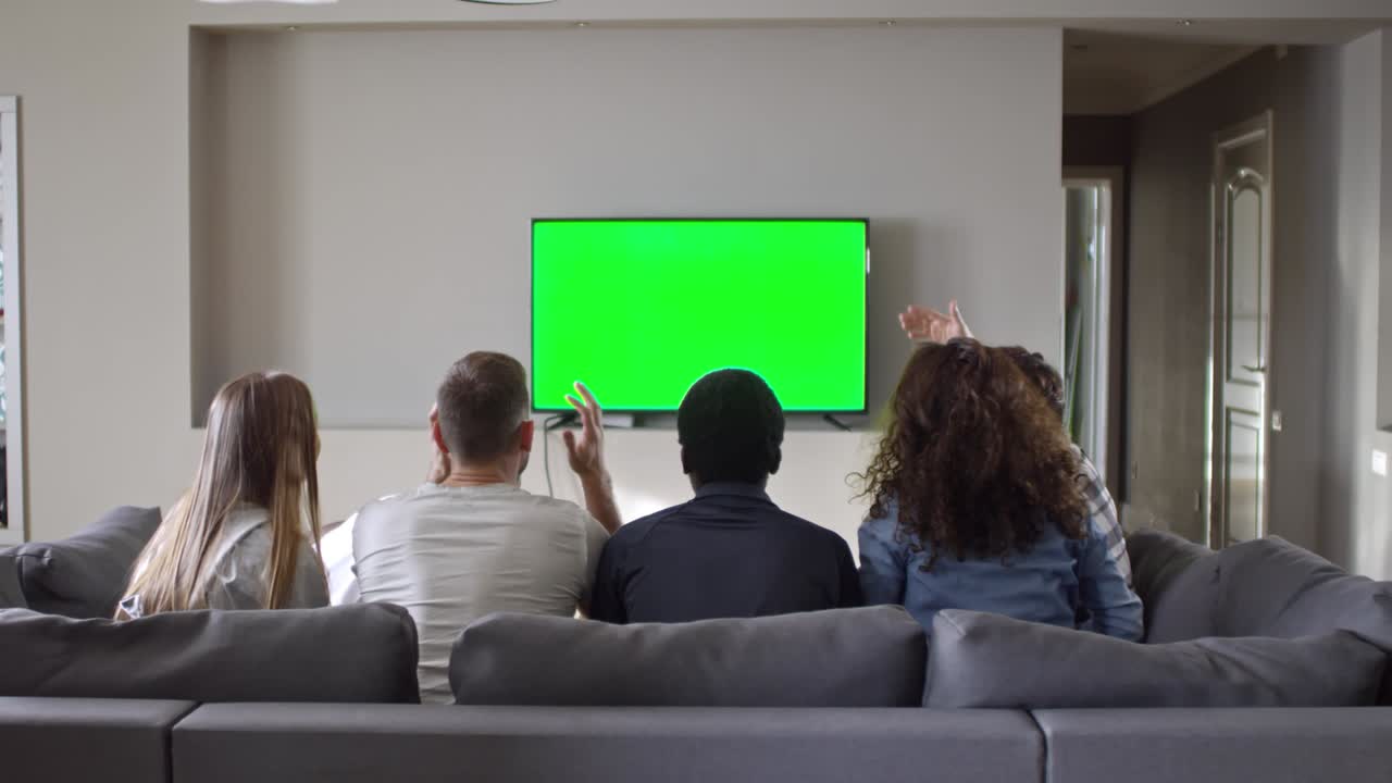 Amici gioiosi che guardano una partita sportiva in TV con schermo Chroma Key