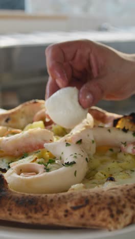 chef putting mozzarella on top of the gourmet octopus pizza