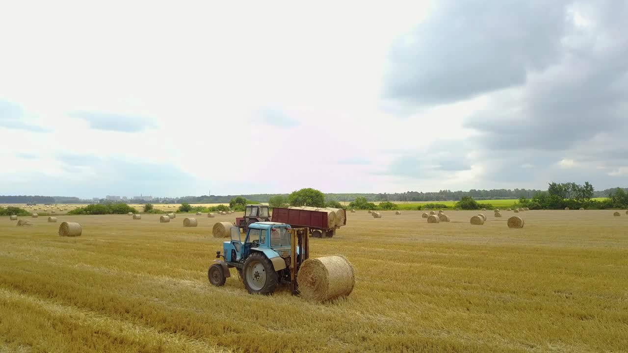 Tractor Loading Hay Bales. Tractor loading hay bales on truck trailer during agricultural works