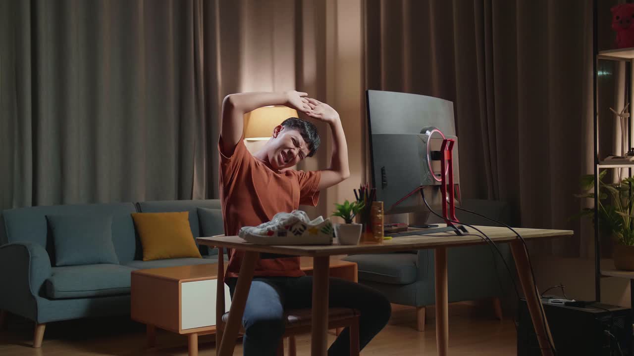 아시아 소년 신발 디자이너가 집에서 데스크에서 일한 후 스트레칭을 하고 있습니다.