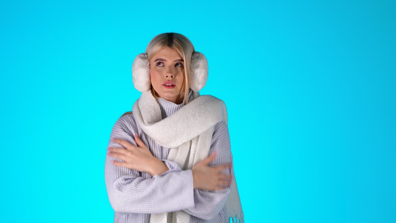 joven rubia sintiendo frío, temblando, soplando en sus manos para calentarse, colorida toma de estudio