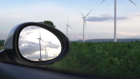 progressive ideal of wind turbine reflected in side mirror of electric vehicle.