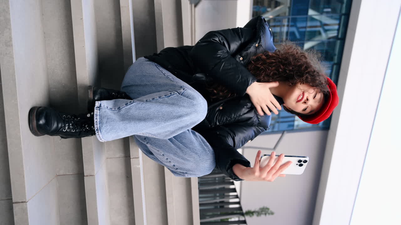 A young woman blogger influencer in red hat recording herself on smartphone