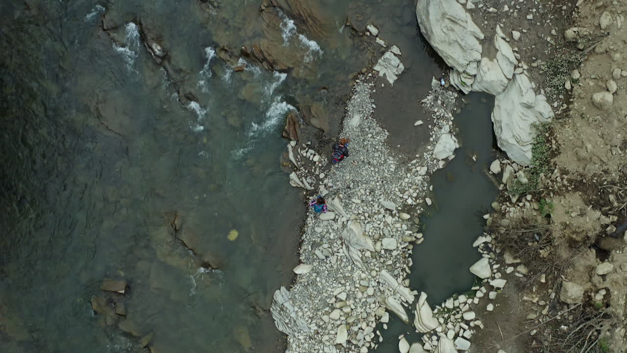 una pareja caminando por un río rocoso disfrutando de un cálido día de verano.
