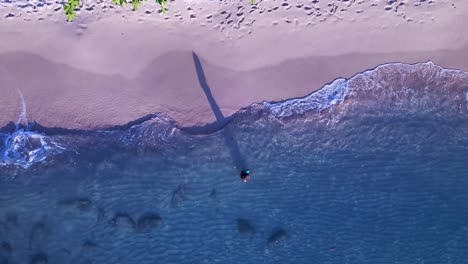 Woman-with-dress-on-beach-in-water-makes-long-shadow