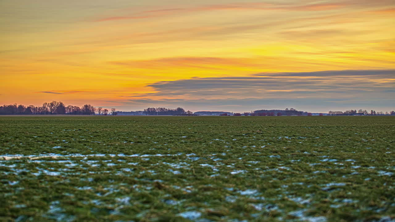 замерзшие поля на фоне огненного неба во время зимнего заката