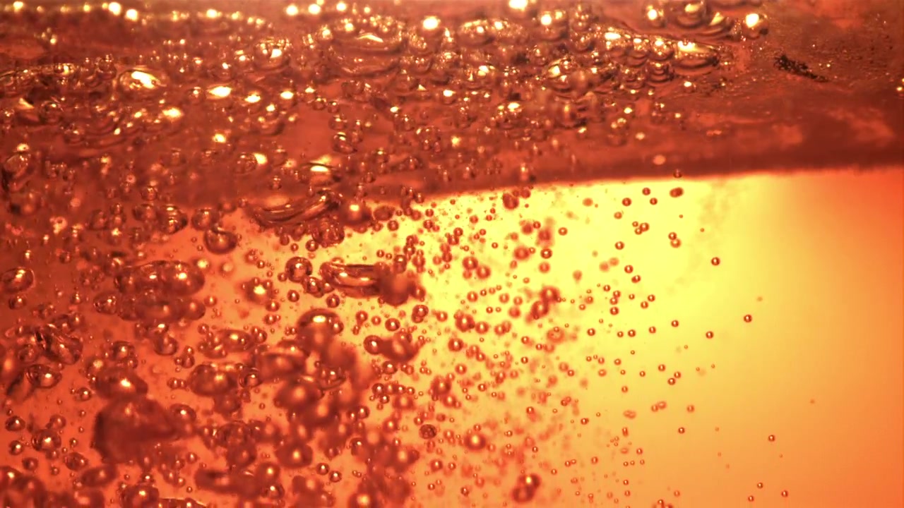 Bolle ambrate scintillanti che salgono in un liquido dorato