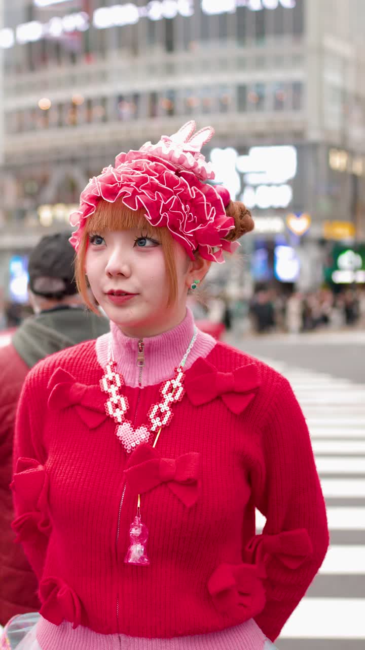 Una donna in vivace stile decora rosa ride mentre si trova a un affollato attraversamento pedonale di Tokyo.