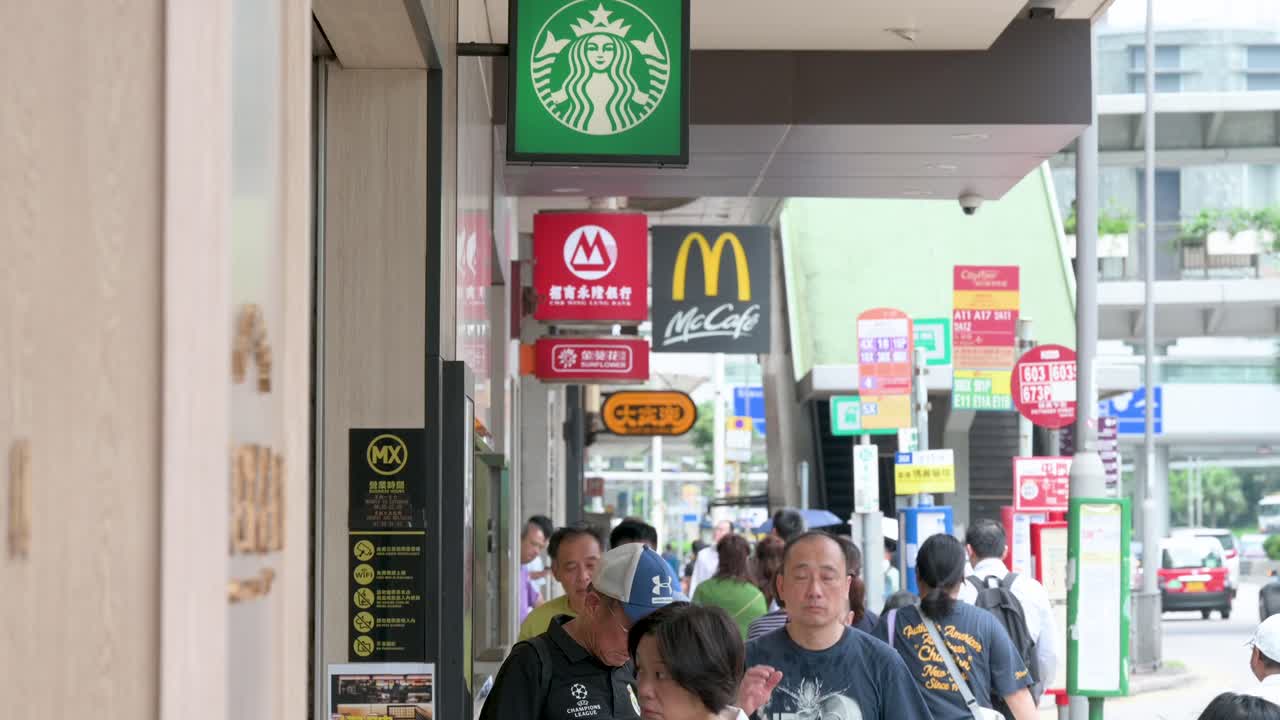 A bustling street scene captures pedestrians strolling by the iconic Starbucks and McDonald's locations in Hong Kong, China.