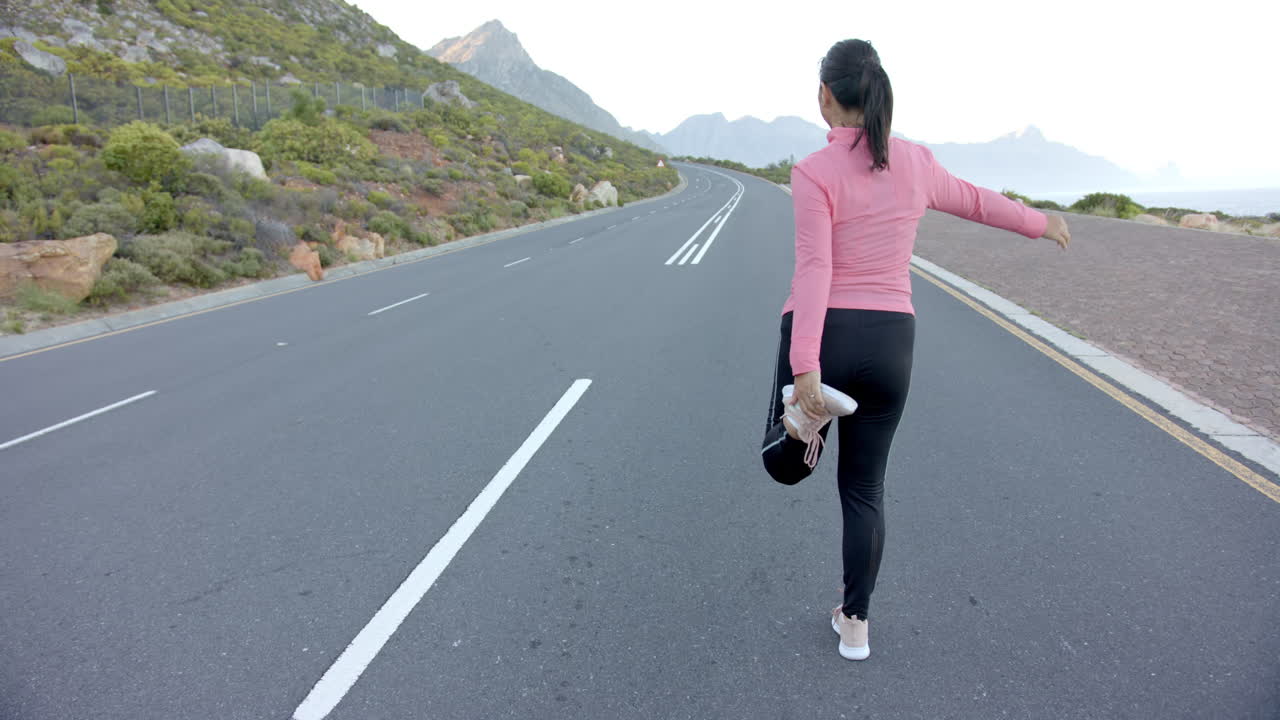 Jogging on mountain road, woman in athletic wear enjoying outdoor exercise, copy space