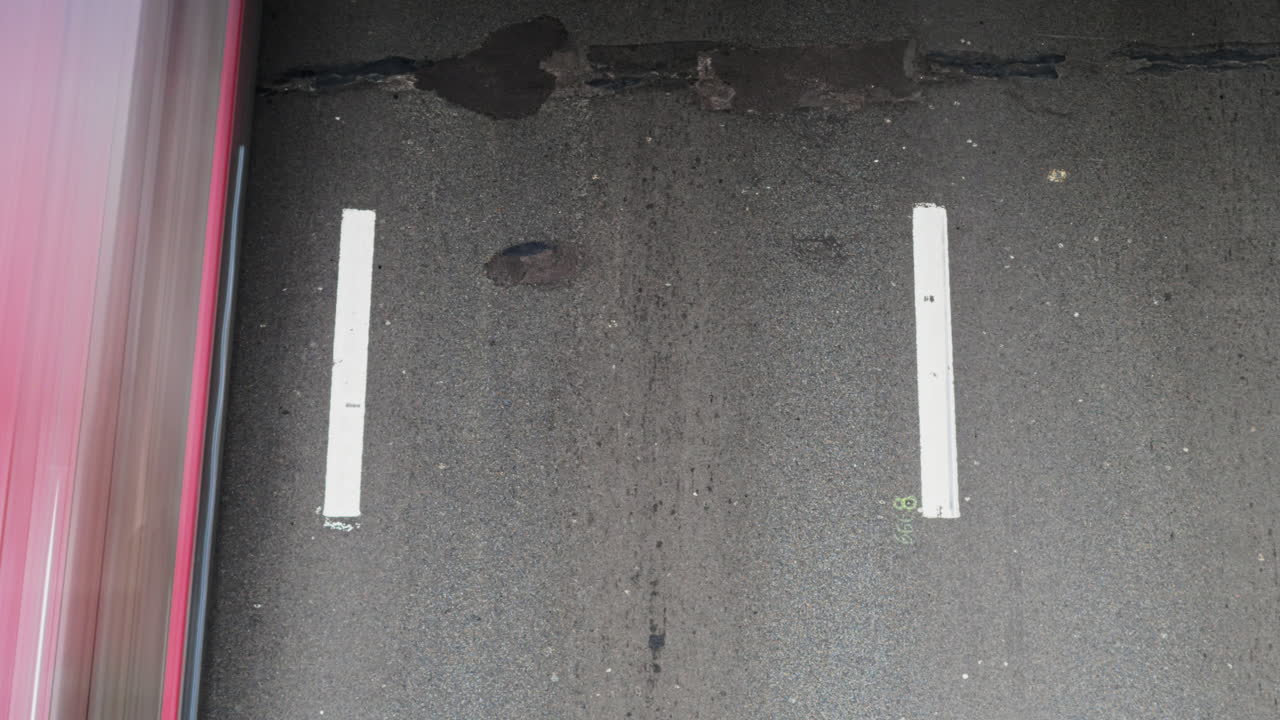 Close-up straight down timelapse showing a single lane with worn white lines on aged asphalt