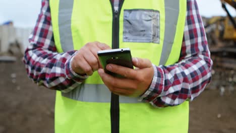 trabajador masculino usando teléfono móvil en el depósito de chatarra 4k