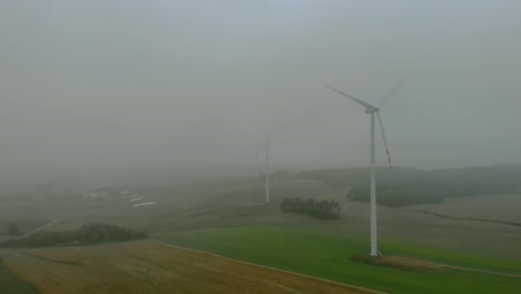 在霧<unk>的早晨在風力發電廠的空中拍攝,風車在田野中靠近