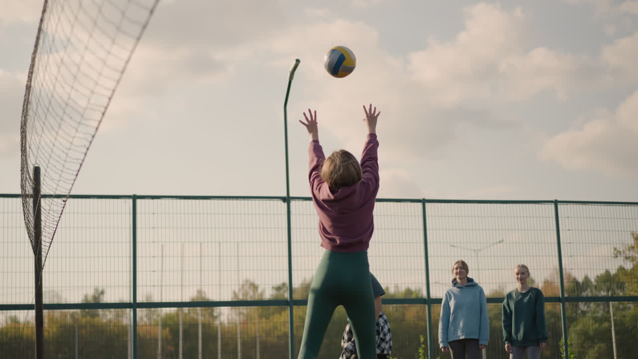 배구 코치와 함께 배구 선수가 점프하고 공을 고 땅에 떨어지고, 두 명의 아마추어가 배경에서 지켜보고, 팀워크, 운동과 액션을 보여주고 있습니다.
