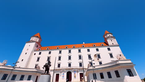 entrance faсade of the beautiful white bratislava castle from low angle perspective. view on the monument of svatopluk at the foreground