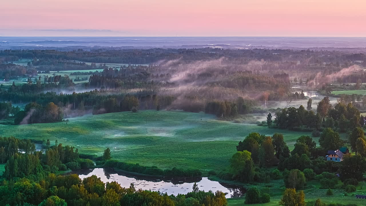 Peaceful sunrise timelapse over misty, green landscape with calm skies
