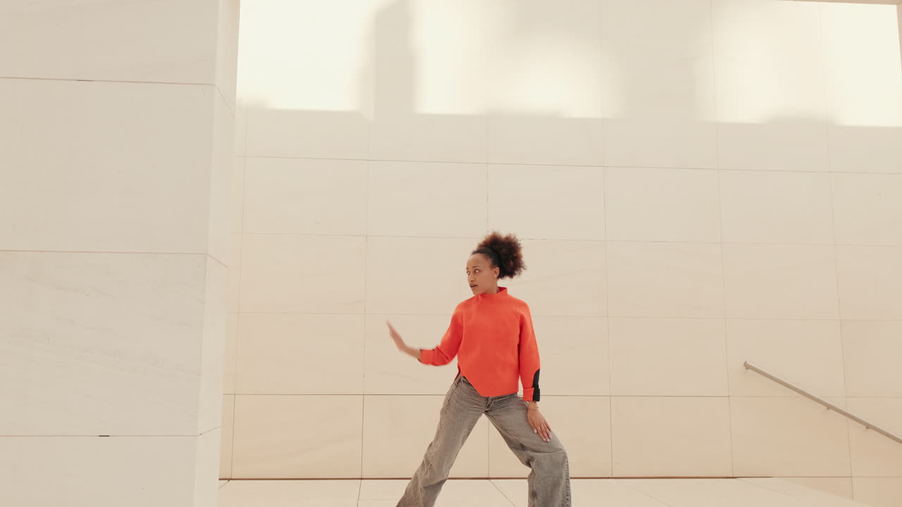 Young Woman Dances Joyfully in Orange Sweater