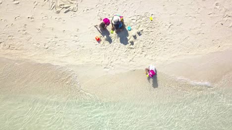 aerial top view of young mum with children building a sandcastle on shore