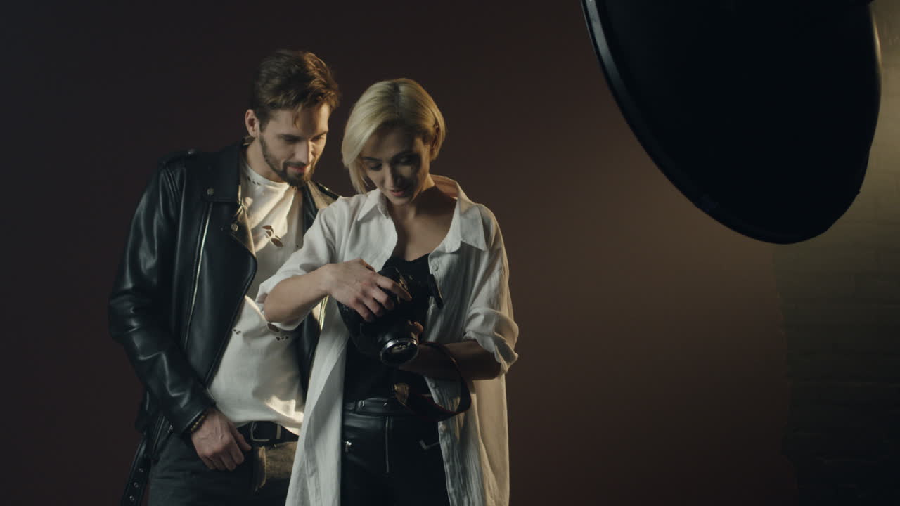 unge mandlige modeller og kvindelige fotografer viser billeder efter fotoshoot på kameraets skærm, mens de smiler