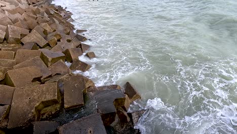 waves hitting concrete blocks on the shore