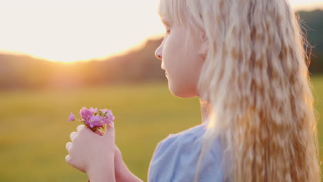 Blondes-Mädchen-6-Jahre-Alt-Mit-Einem-Strauß-Wildblumen,-Die-Bei-Sonnenuntergang-Auf-Dem-Feld-Stehen,-Seitenansicht-Langsam