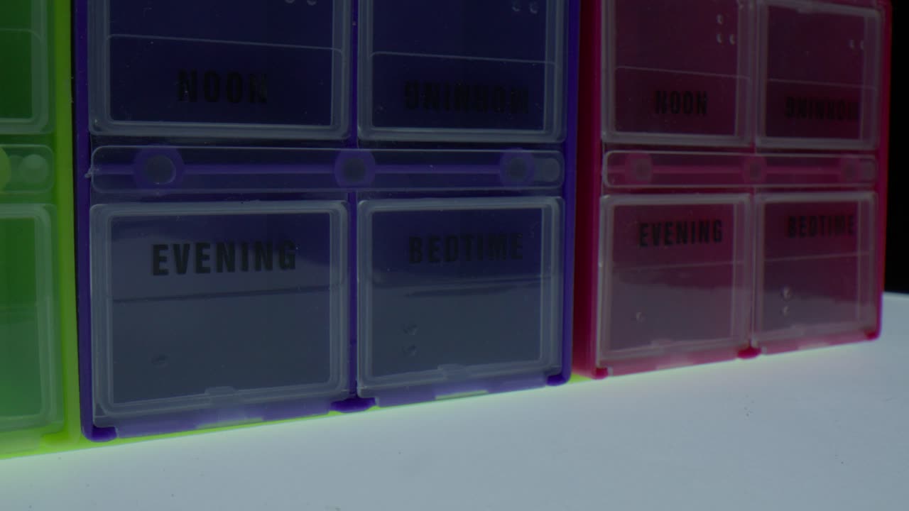 Macro close up of pill boxes labeled evening and bedtime slowly spinning in studio lighting representing medication routine healthcare organization and daily wellness management