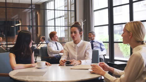 Female-business-colleagues-talking-in-the-cafe-at-their-workplace