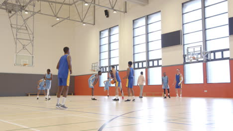 playing basketball, team practicing drills in indoor gymnasium, preparing for game