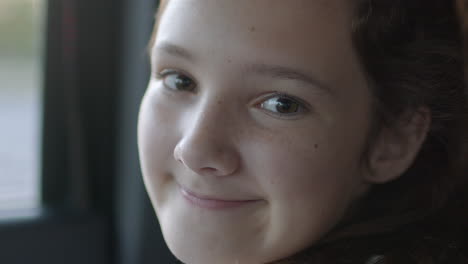 Portrait-of-a-cute-young-girl-riding-in-a-car-and-smiling-at-camera