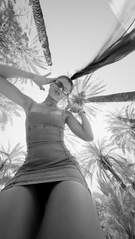 stylish woman posing under palm trees in black and white