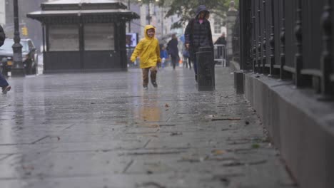 kid playing in the rain with a yellow jacket new york city