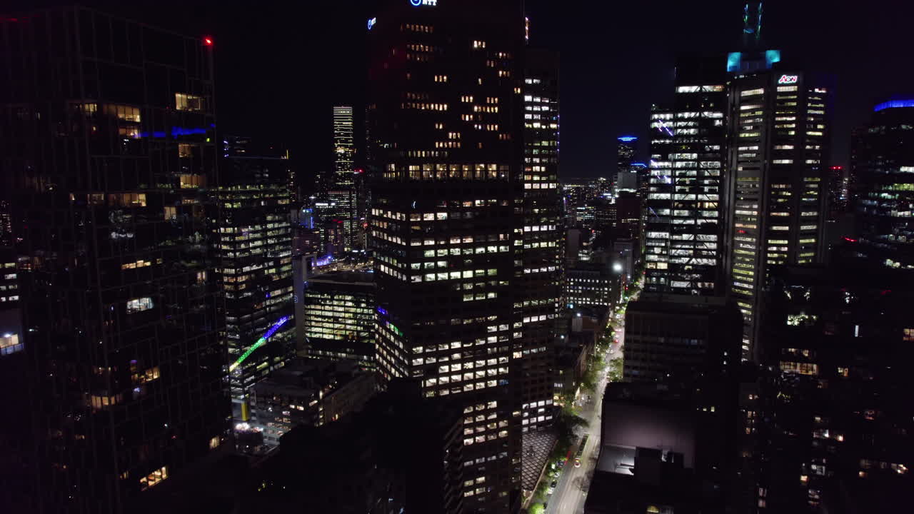 Aerial view backwards in front of high-rise of East End, Melbourne, night-time