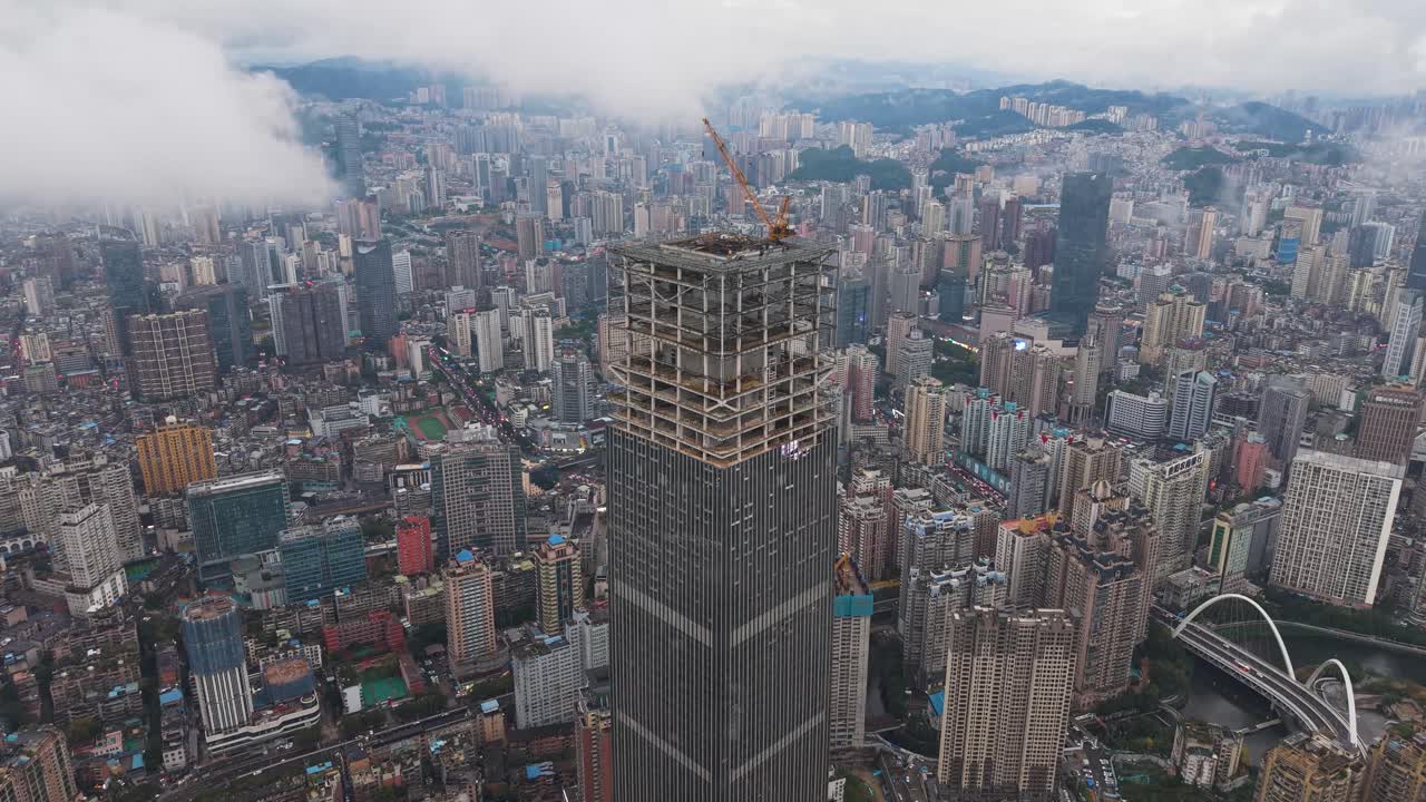 Orbiting drone shot of the massive Hengfeng Guiyang Center Tower 1 under construction, with the cityscape of Guiyang, China