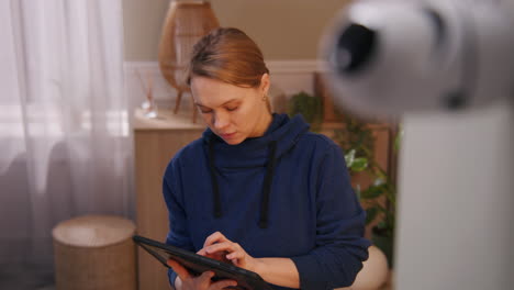 woman using tablet in front of security camera at home