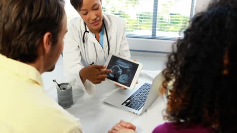 Female-doctor-with-digital-tablet-showing-ultrasound-scan-of-baby-to-couple