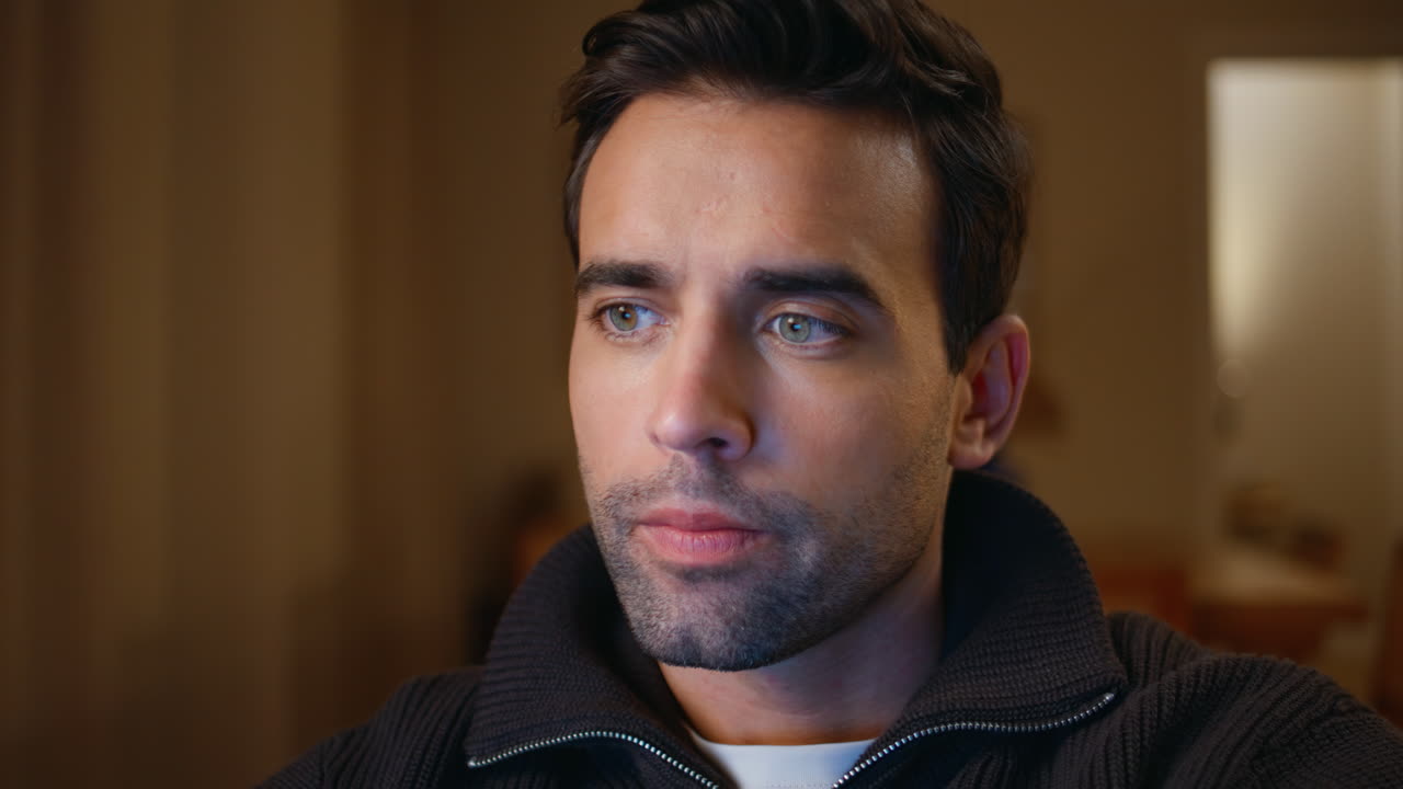 Serious student studying late looking laptop screen in dark living room closeup