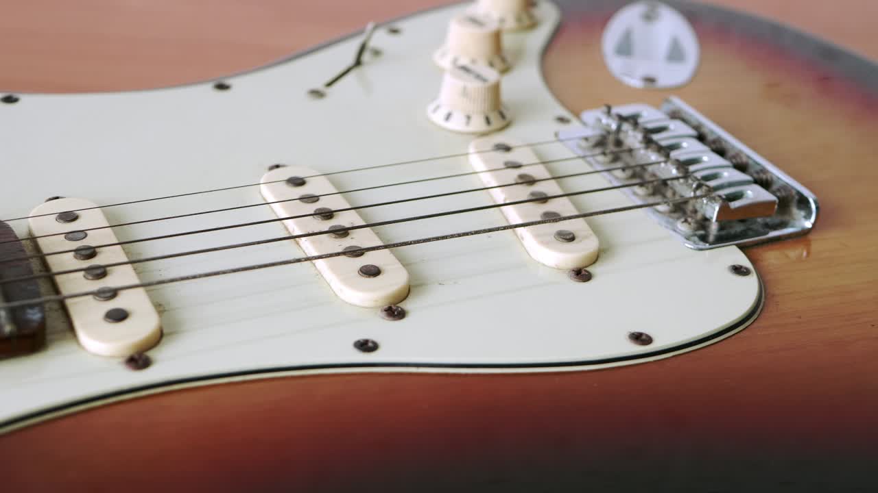 deslice el movimiento de la vieja guitarra eléctrica con un patrón fino de cuerdas de guitarra colocadas sobre una mesa de madera