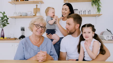 familia feliz saludando y mirando la cámara mientras tiene una videollamada divertida en la cocina