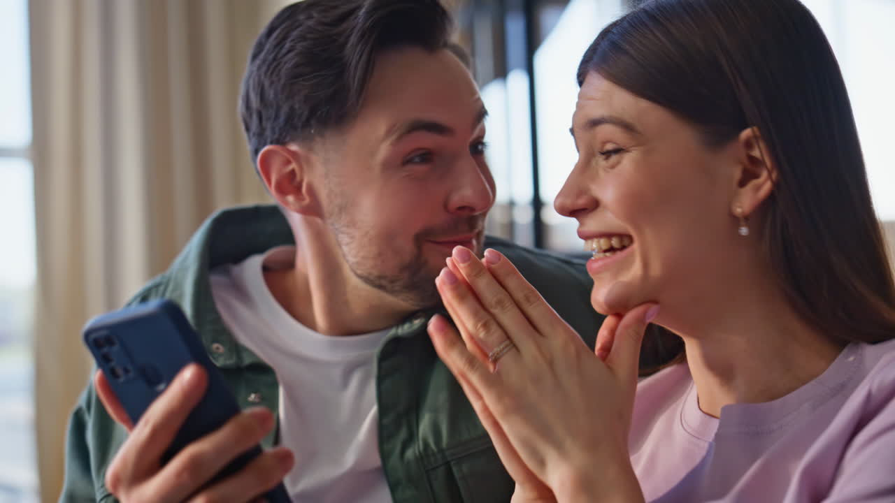 Positive man checking smartphone at room closeup. Couple winning achievement