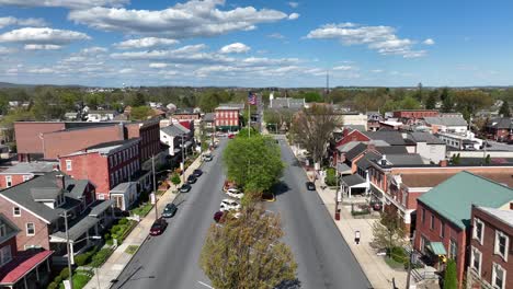 Aerial-flyover-small-american-town-with-waving-flag-during-sunny-spring-day