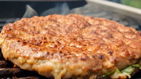 closeup of a juicy burger patty grilling on a bbq grill