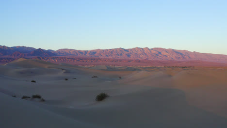 drone flying over massive sand dunes beautifully lit by sun during golden hour