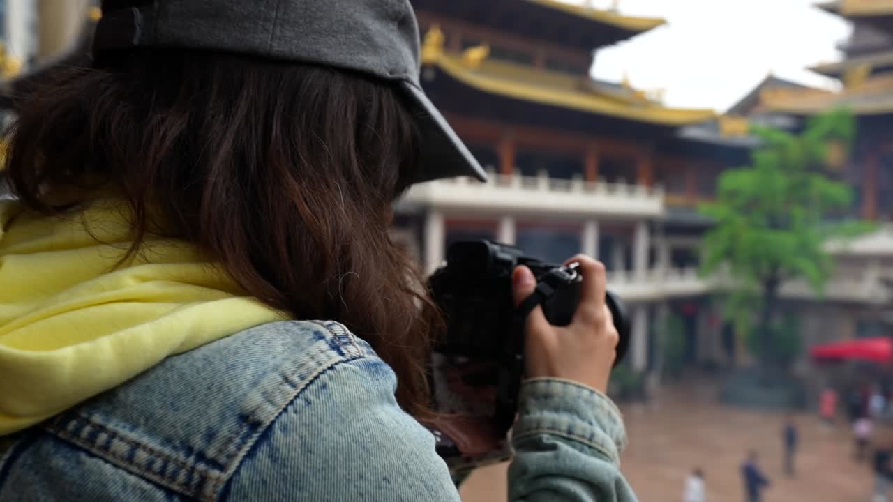 Rear shot of a woman taking photos with a professional camera of the Jingan Temple yard and incense burner, Shanghai, China