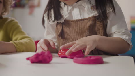 primer plano de una niña jugando con plastilina sentada en un escritorio en una escuela montessori