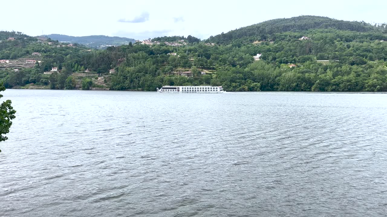 포르투갈 의 초록색 언덕 을 배경 으로 타구스 강 을 가로지르는 관광 크루즈 선박