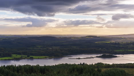 time lapse of rural farming landscape with lake, forest and hills during a cloudy evening sunset viewed from above lough meelagh in county roscommon in ireland