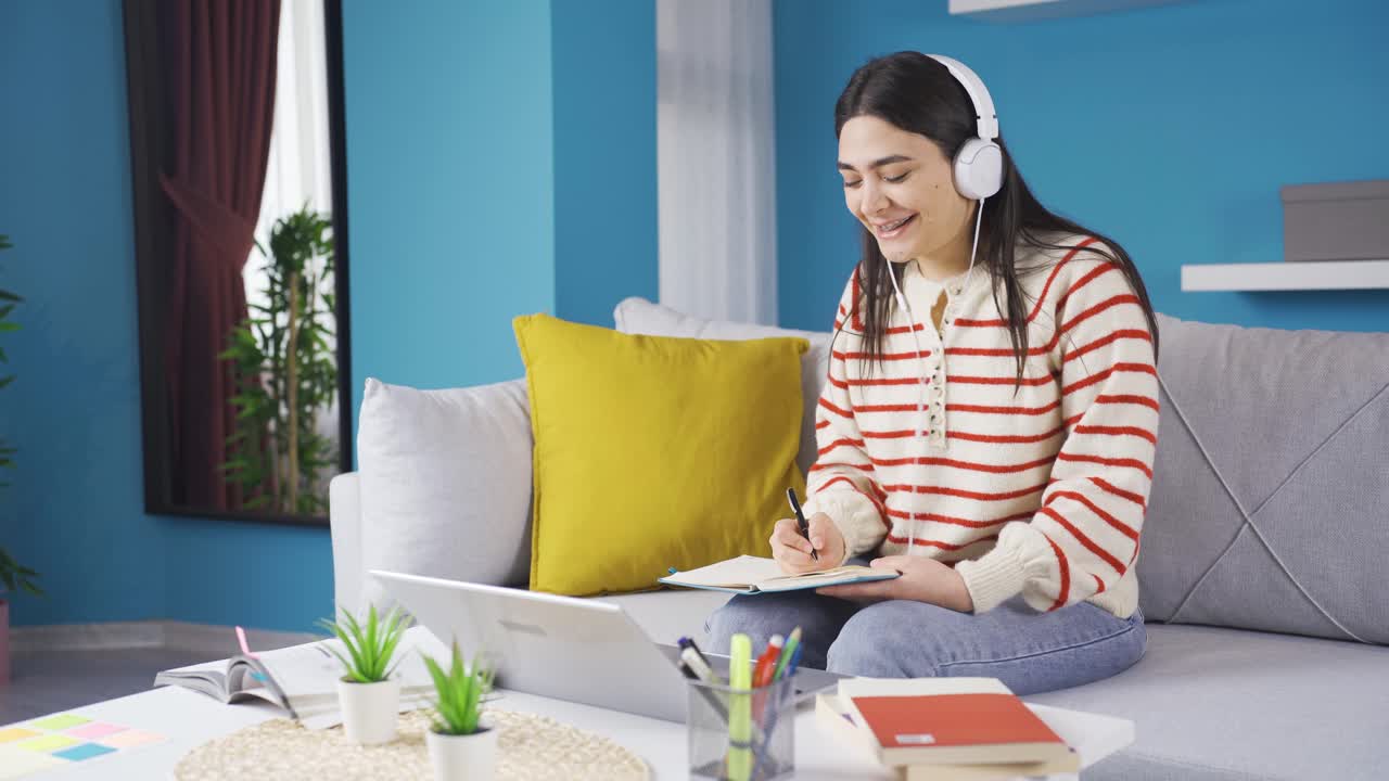 행복하고 재미있는 젊은 여성이 집에서 공부하고 있습니다.